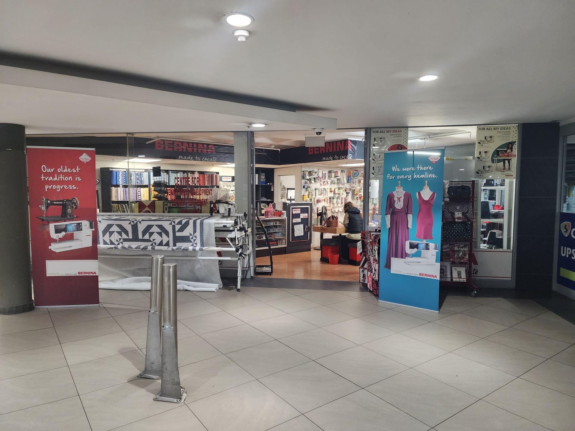 Entrance to a sewing and fabric store with display banners and sewing machines inside.