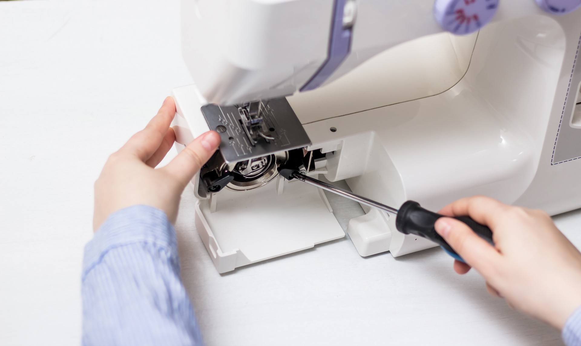 Sewing machine repair. Screwdriver. White sewing machine. Sewing content. Repair of household appliances.