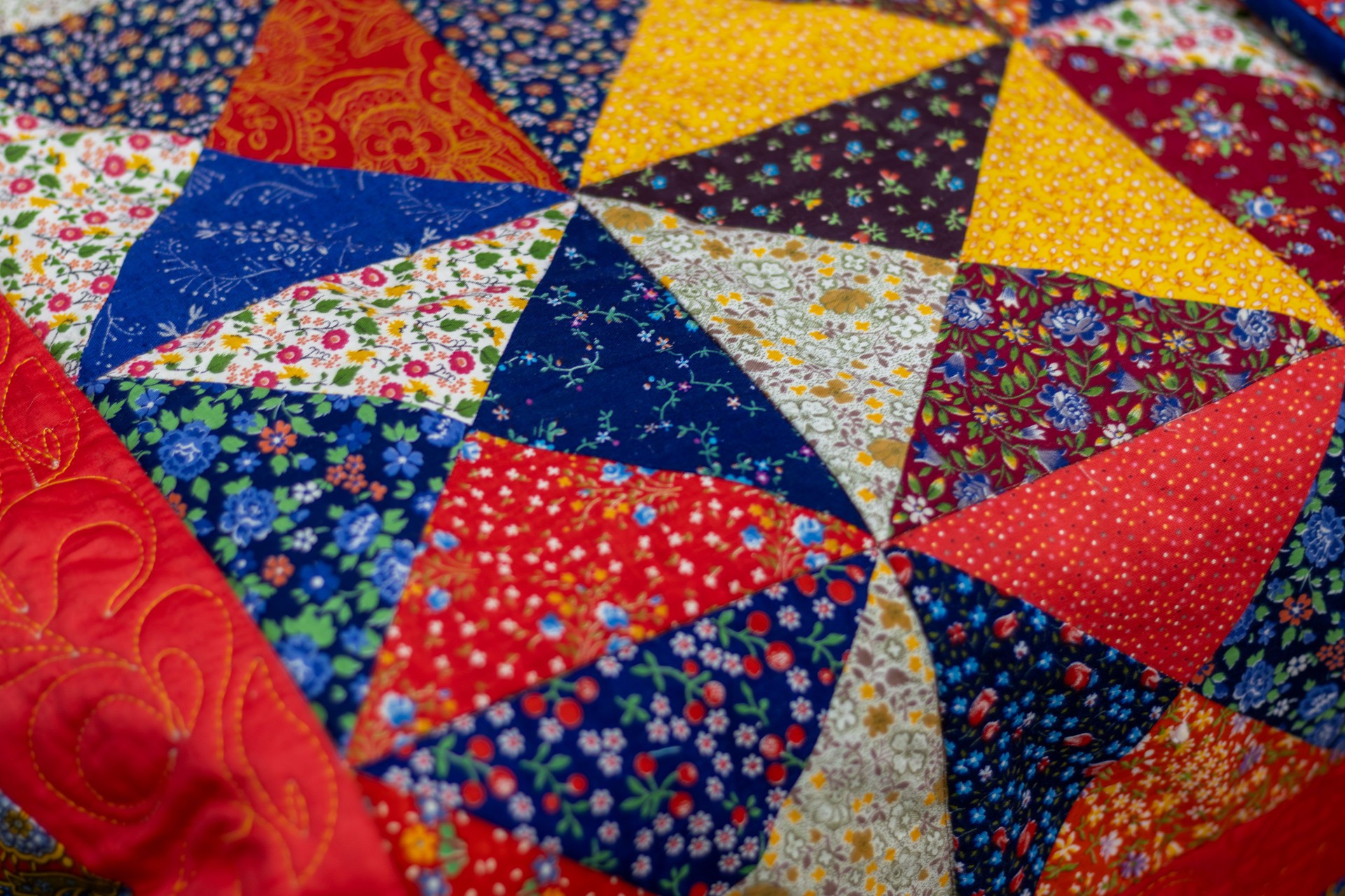 Bright, colorful patchwork quilt featuring variety of floral patterns and symmetrical designs. Mottled background