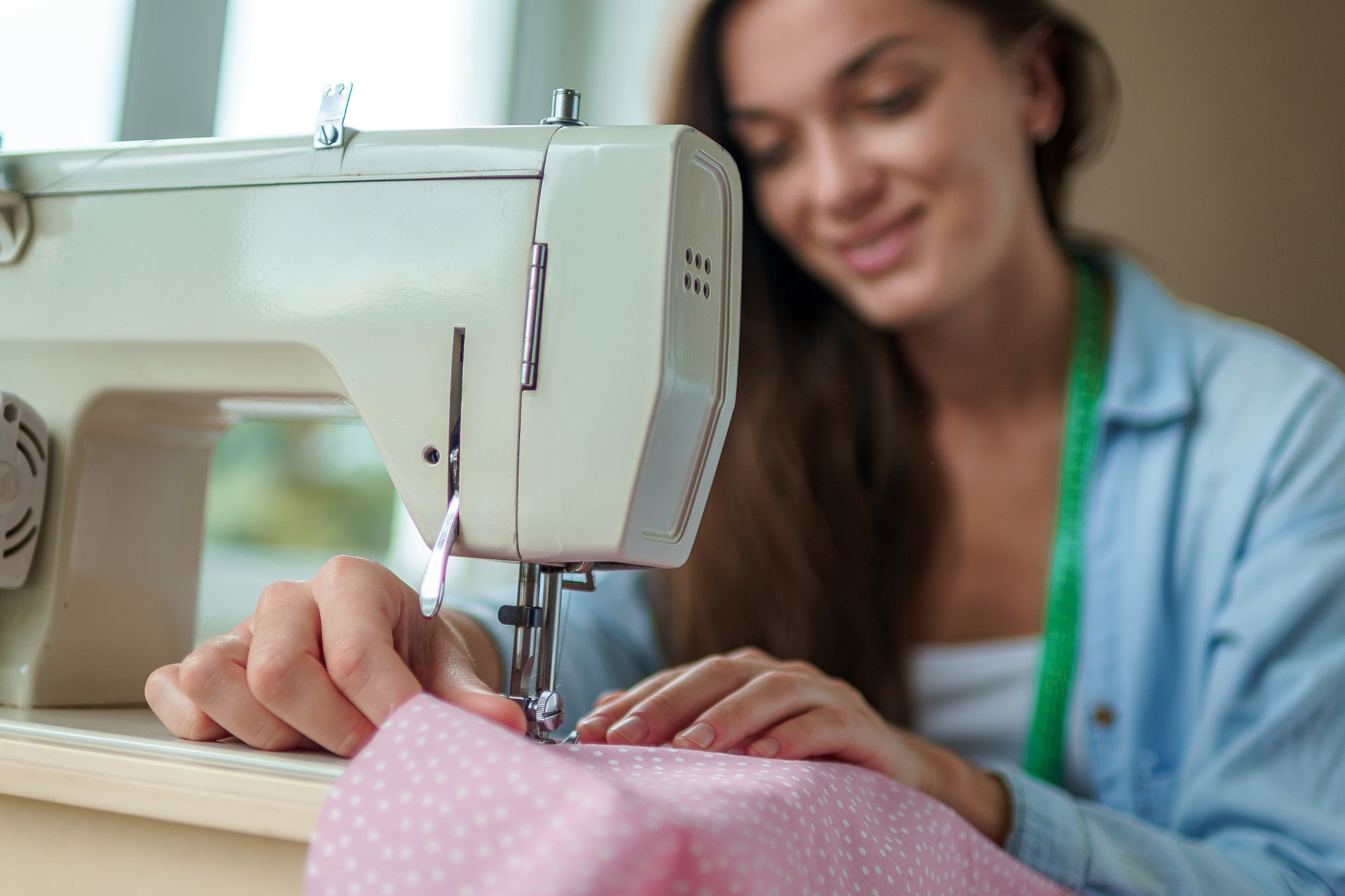 Seamstress using electric sewing machine and different accessories for sewing clothes