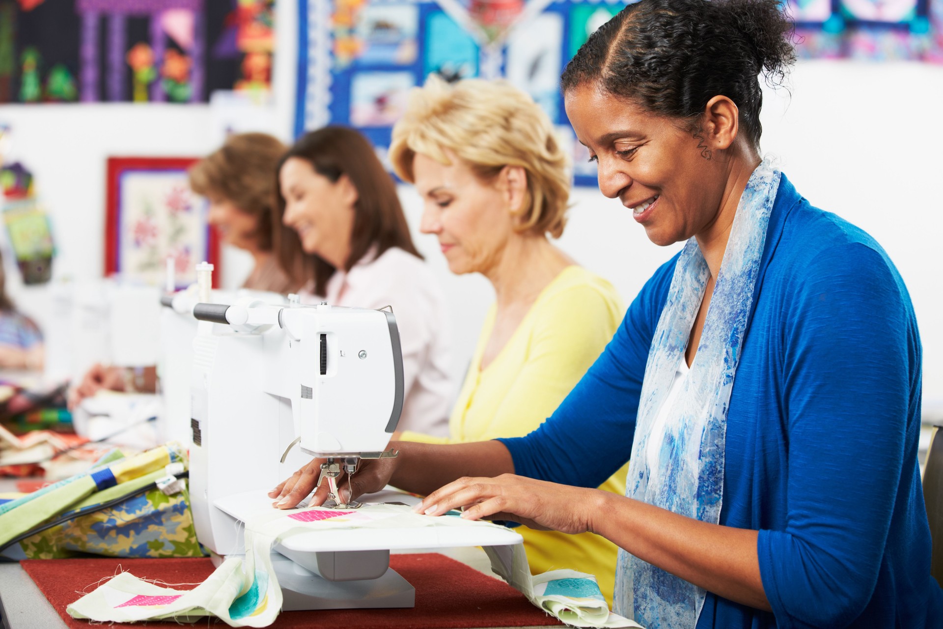 Group Of Women Using Electric Sewing Machines In class